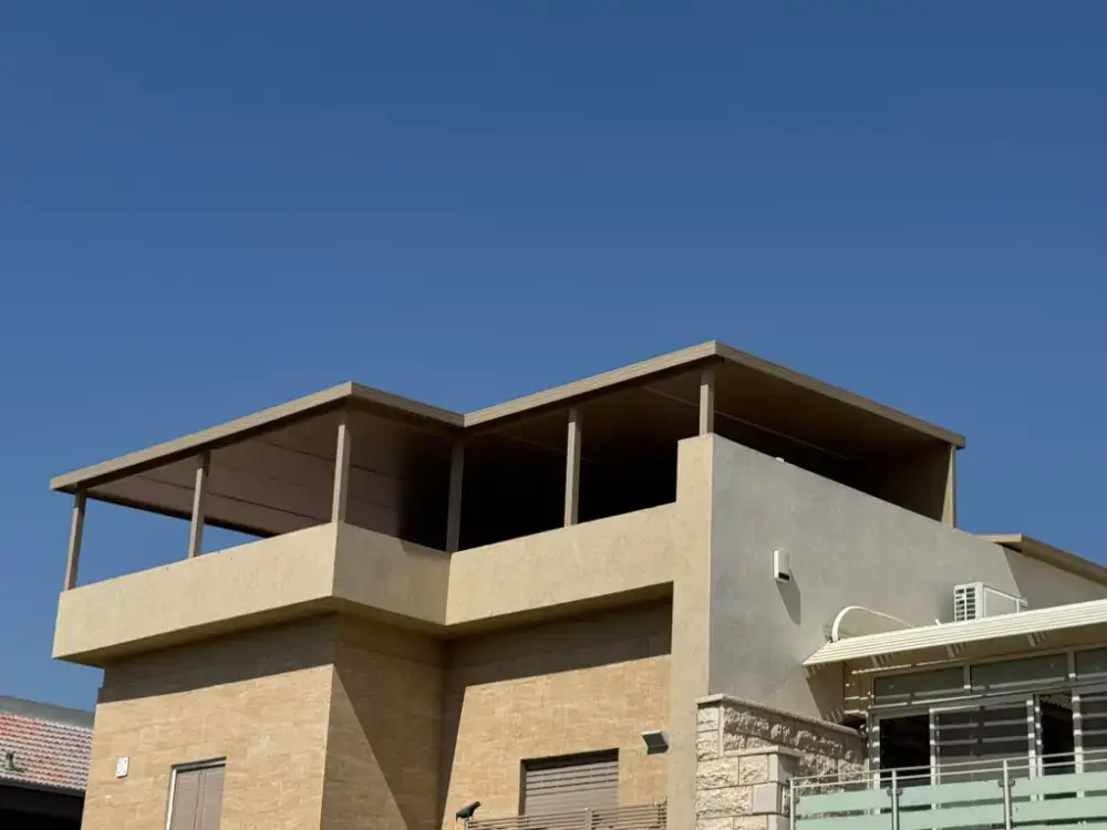 פרגולה בגוון בז' על עמודים עם קירוי אטום בקומת הגג של בית