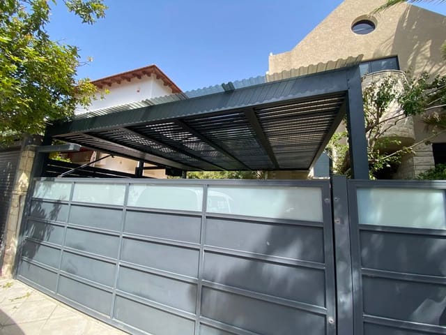 פרגולת חנייה בטיחותית ומעוצבת – הצללה מלאה לרכב מאחורי שער