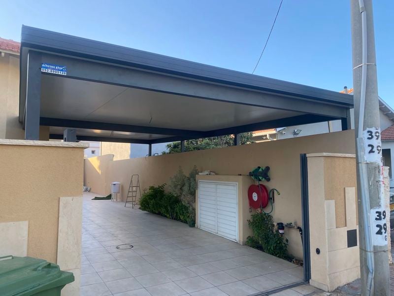 פרגולת חניה אנתרציט עם קירוי אטום מעל שביל הכניסה לבית