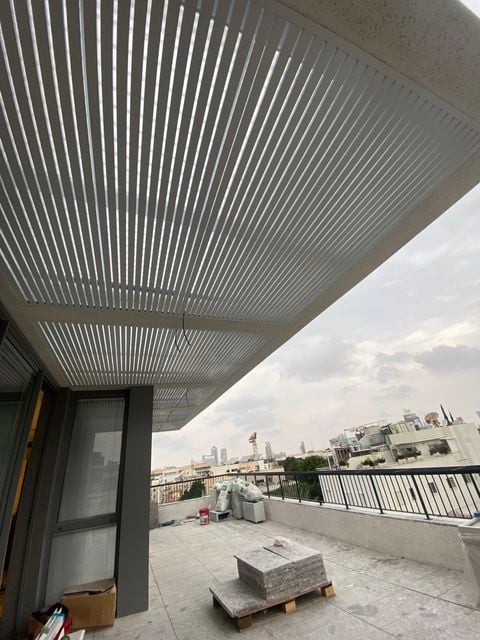פרגולת שלבים לבנה בתקרת מרפסת גג עירונית בסיום ההתקנה