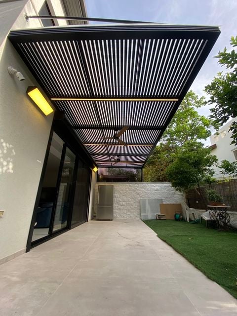 קירוי שלבים עם פס לד ומאוורר מעל חצר מרוצפת – דגם פרגולה שחורה תלויה