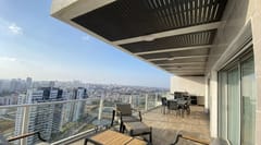 מרפסת מגדל רחבה עם פרגולה תלויה כהה, פינת אוכל ומטבח חוץ