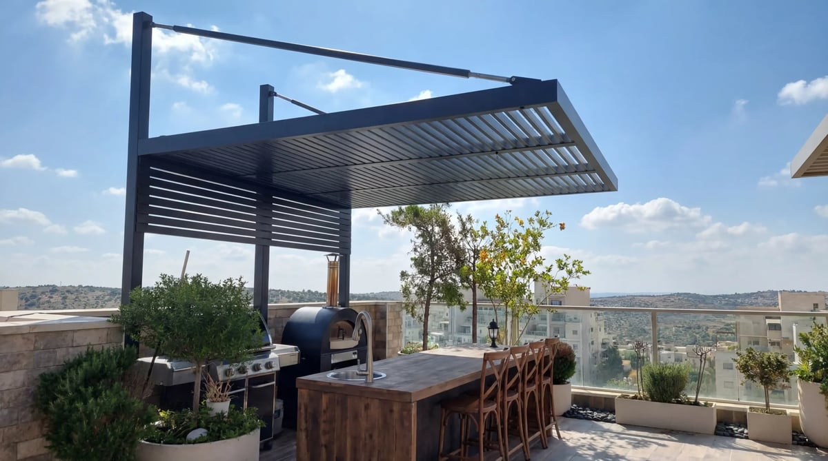 פרגולה אפורה עם מוטות תמיכה ודופן רפפות מעל מטבח חוץ בגג