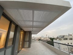 פרגולת שלבים לבנה לאורך מרפסת גג עם מעקה ונוף העיר