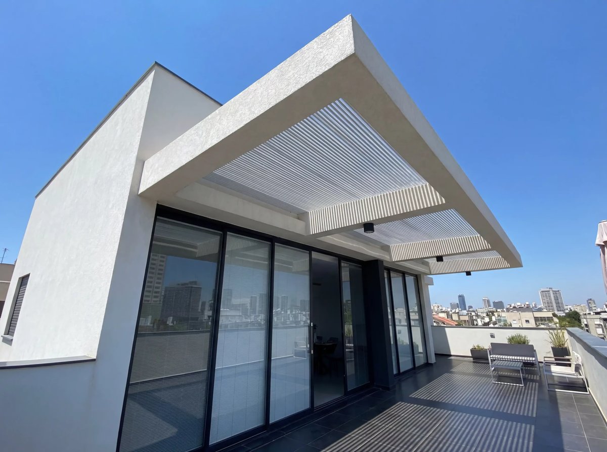 מבט מהמרפסת על פרגולה לבנה מרחפת מעל חלונות זכוכית גדולים